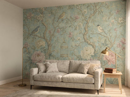 Aqua chinoiserie wallpaper on a wall beside plain plaster, with a grey sofa and a small table