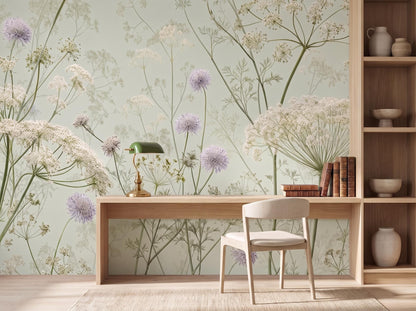 Pale celadon cow parsley wallpaper behind a light oak desk, chair and open shelving
