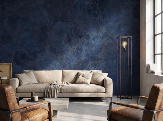 Navy blue plaster wall mural behind a linen sofa, with leather armchairs and a concrete coffee table