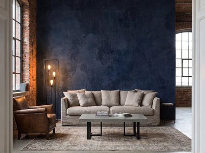 Navy plaster mural on a loft wall between exposed brick and tall windows, with a linen sofa and a leather armchair