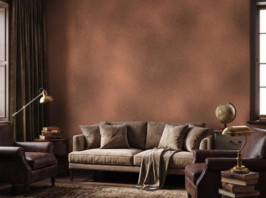 Warm rust limewash wall behind a linen sofa, leather armchair, brass lamp and globe