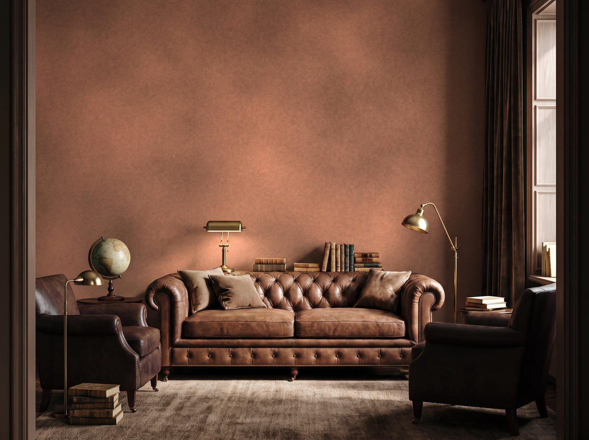 Wide room with the warm rust limewash wall, a leather chesterfield, books and a globe